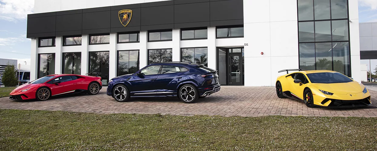Three luxury cars parked outside a dealership.